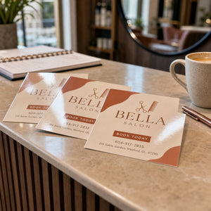 High-Gloss Postcards in use - spread in a loose overlapping row on a salon desk beside a pen and a coffee