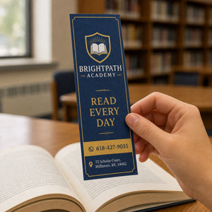 Linen Bookmarks in use - held in one hand above an open book in a school library